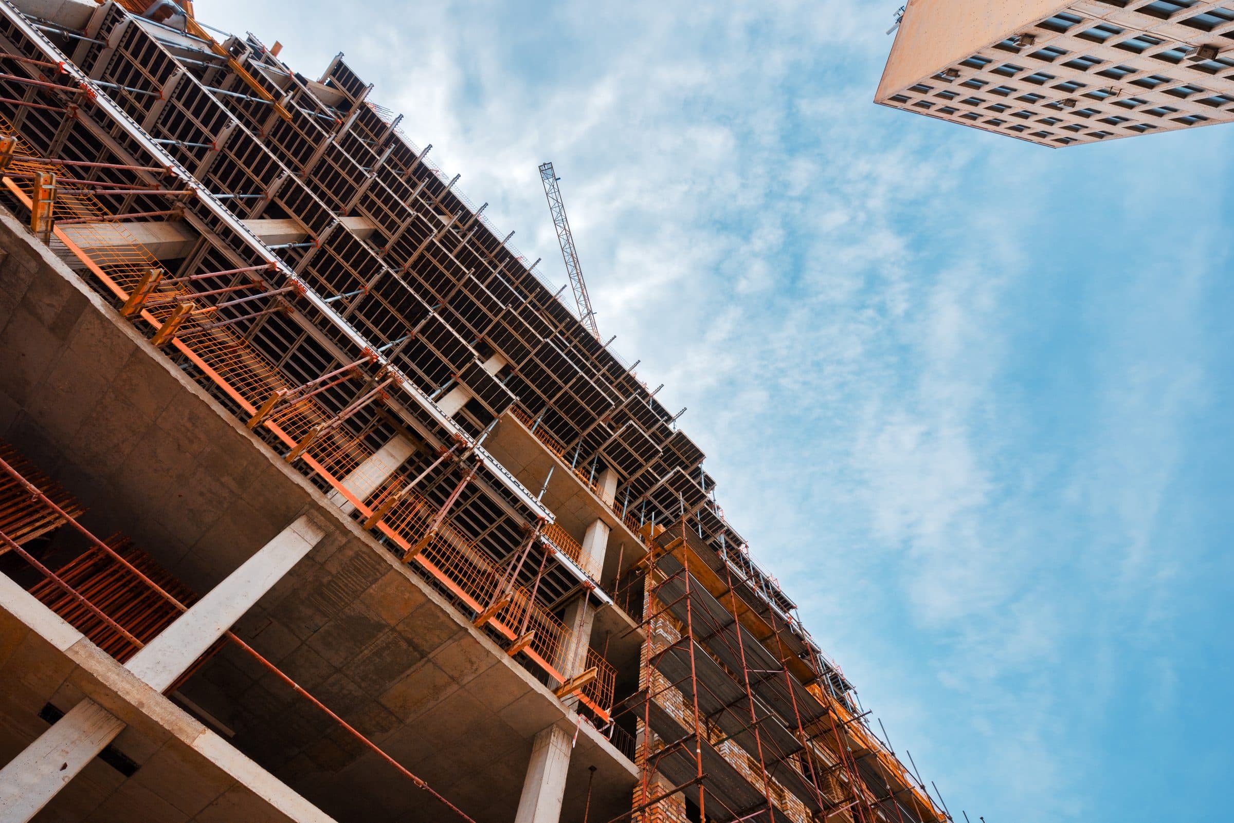 Looking up at a high-rise building under construction with a crane