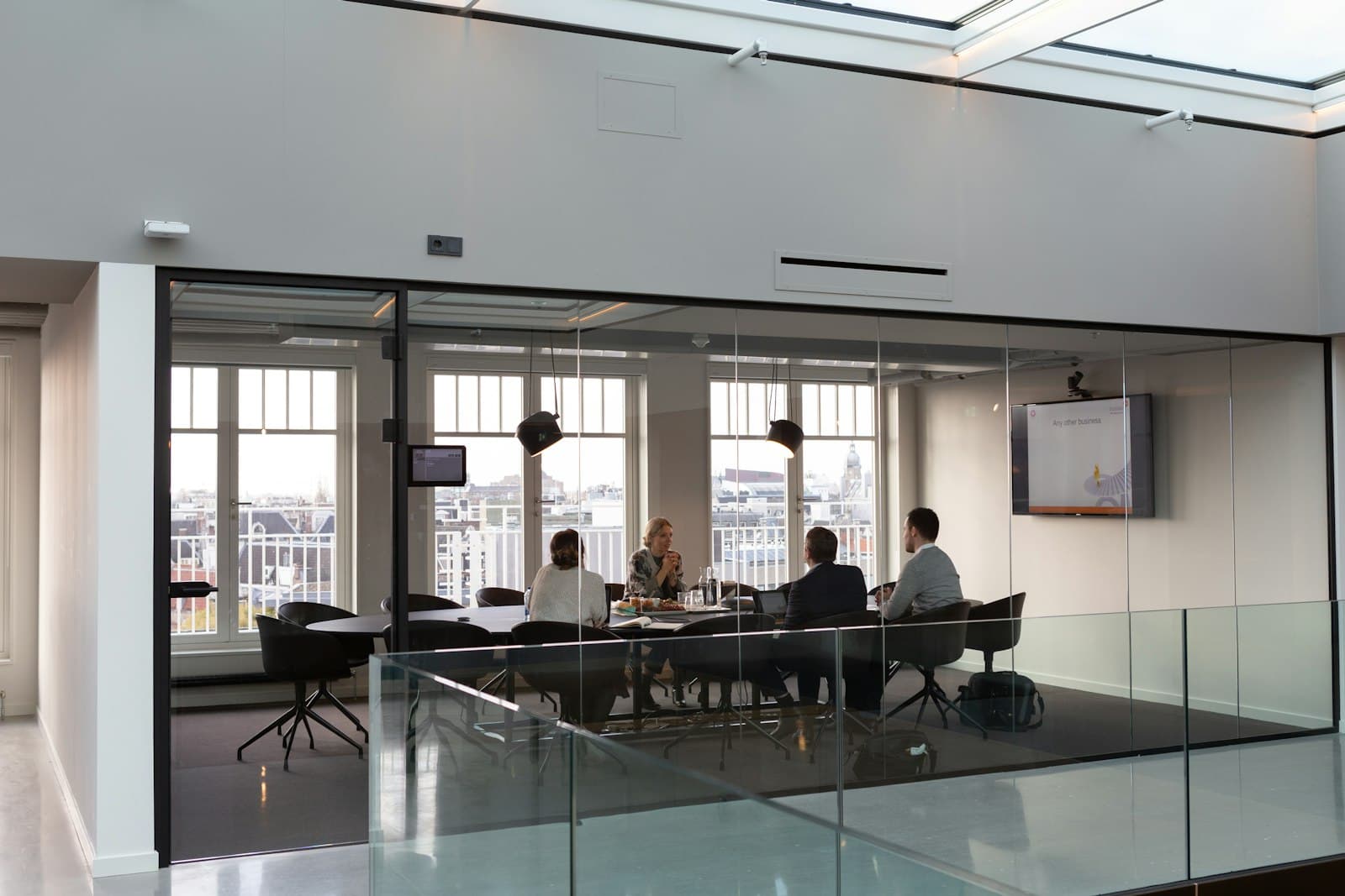 Glass-walled meeting room with tall windows looking over the city