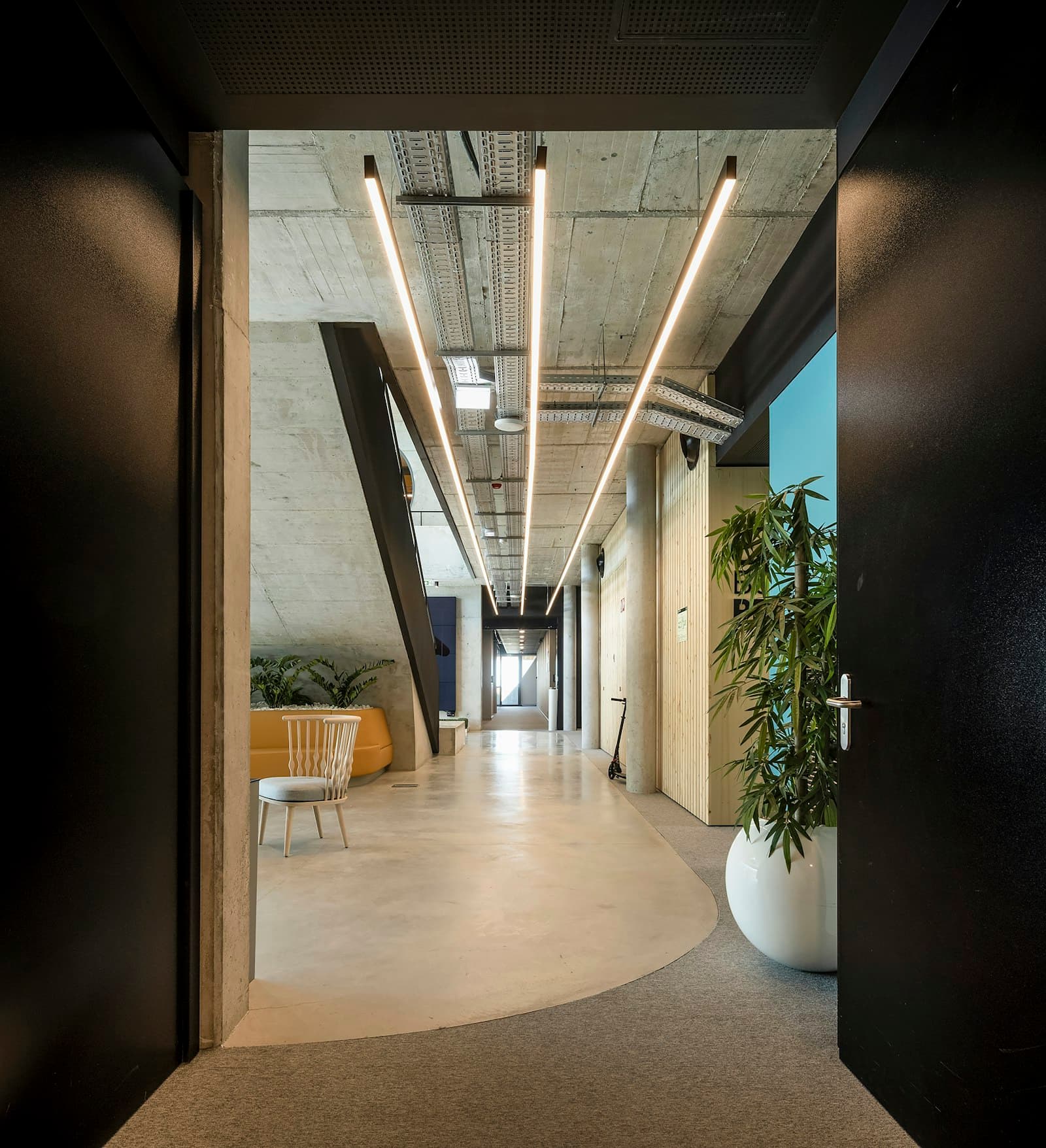 Corridor with exposed concrete ceiling and linear lighting
